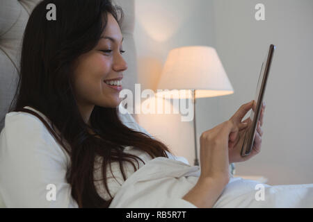 Frau mit digital-Tablette im Schlafzimmer Stockfoto