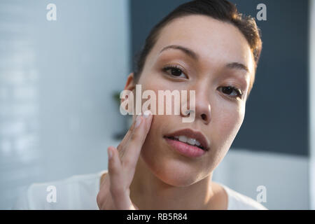 Frau Anwendung Lotion auf ihr Gesicht in Bad Stockfoto