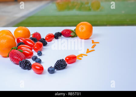 Bunte Früchte Anordnung in einem weißen Hintergrund mit dem Wort Leben aus Tangerine Schalen und Blick auf grüne Gras außerhalb des Fensters. Stockfoto