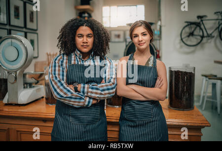 Portrait von zuversichtlich Baristas mit Waffen im Coffee Shop gekreuzt Stockfoto