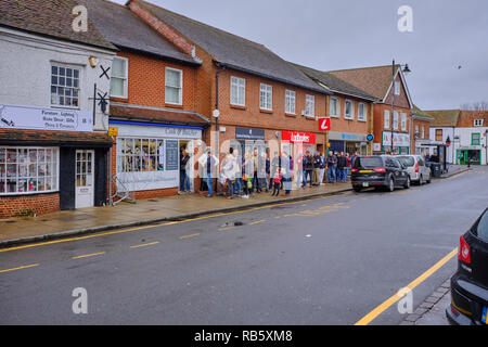 Eine lange Schlange von Menschen auf dem Bürgersteig warten die örtlichen Metzgern Shop in der Nähe von Weihnachten in Thatcham High Street, Berkshire, Großbritannien Stockfoto