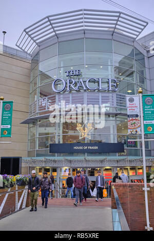 Menschen Betreten und Verlassen des Oracle Shopping Centre durch den Haupteingang, der auch mit Weihnachtsschmuck dekoriert ist, Reading, Großbritannien Stockfoto