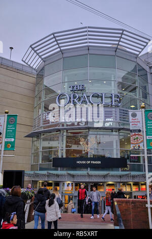 Menschen Betreten und Verlassen des Oracle Shopping Centre durch den Haupteingang, der auch mit Weihnachtsschmuck dekoriert ist, Reading, Großbritannien Stockfoto