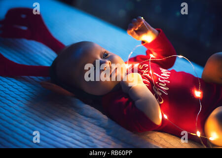 Baby Mädchen mit Santa's Crawlen mit sehr entschlossene Gesichtsausdruck. Erstes Weihnachten. Stockfoto