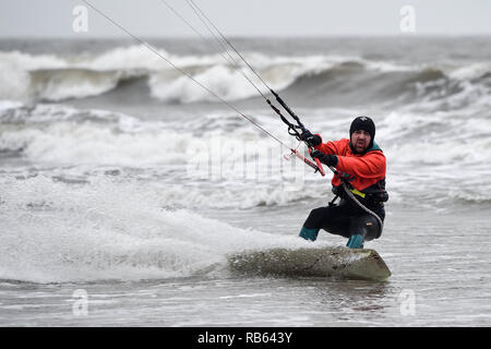 Ein Kite Surfer die stürmische Wetter am Rest Bay, Porthcawl, in windigen Bedingungen auf der South Wales Küste. Stockfoto