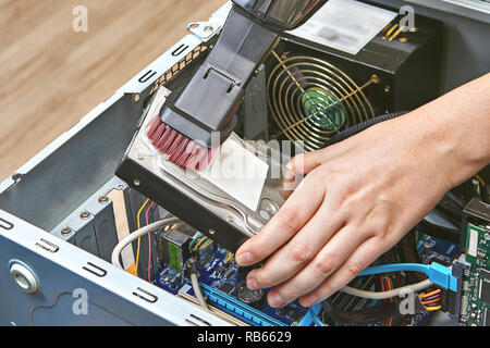 Festplatte des Pcs wird durch einen tragbaren Staubsauger gereinigt. Stockfoto