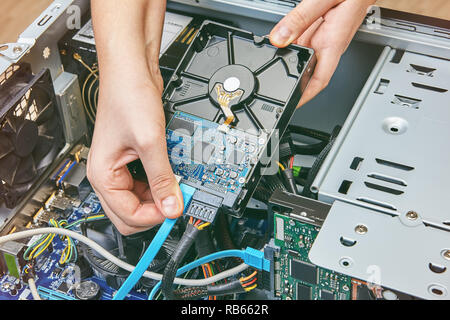 Schließen Sie das SATA-Datenkabel mit der Festplatte des Computers. Stockfoto