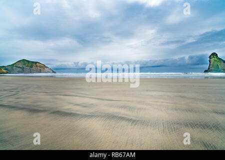 Zwei kleine Inseln auf Wharariki Beach am bewölkten Tag bei Ebbe in Moody atmosphärische Bild Stockfoto