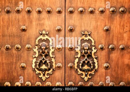 Aus geschmiedetem Metall vintage Golden Door knocker auf braunen Holztür in Cordoba, Spanien Stockfoto