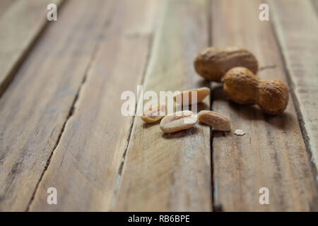 Ungeschälte Erdnüsse auf einem urigen Holz- Oberfläche. In neutralen Farben. Rustikale Küche Stockfoto