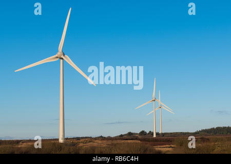 Eine Szene, die erneuerbaren Energien und grüne Energie mit einer Gruppe von drei Windmühlen unter einem wunderschönen blauen Himmel in Nordirland Stockfoto