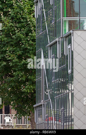 Die Außenseite des studio Gebäude mit Glas und Fliesen- Fassaden gegen Laub. Les Ballets C de la B, Gent, Belgien. Architekt: Architecten Stockfoto