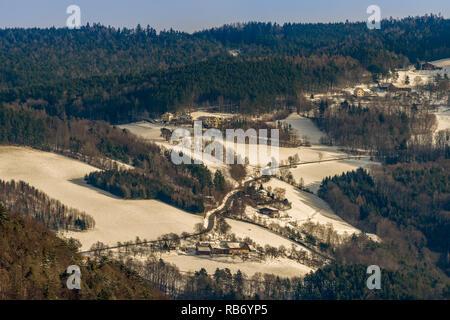 Ländliche hügelige verschneite Landschaft, Straßen, Wald, landwirtschaftliche Gebäude, sonnigen Tag, blauer Himmel Stockfoto