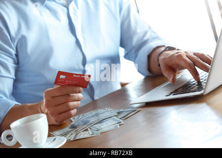 Reifer mann Händler am Tisch im Cafe am Tag sitzen bei einer Tasse Kaffee im Internet surfen auf dem Laptop Holding ec-Karte online shopping close-up Stockfoto