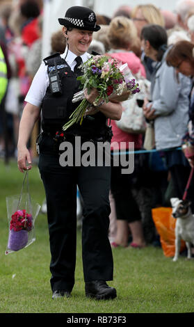 Ein Polizist trägt Blumen und Geschenke als Prinz von Wales und die Herzogin von Cornwall nehmen an der Sandringham Flower Show hielt auf dem Royal est Stockfoto