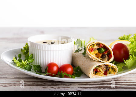 Hausgemachten köstlichen Burritos mit Gemüse und Sauce auf einem hölzernen Hintergrund Stockfoto