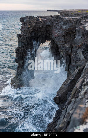 Wellen auf einem vulkanischen Felsen arch in Big Island, Hawaii Stockfoto