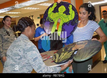 Amaya Mali präsentiert mehrere IV Pole" lilypads" Maj. Carla Cox, pädiatrische klinische Krankenschwesterfachmann. Mali und zwei andere Studenten der Westlake Robotics Club in Austin, Texas, spendete 10 Der Holz- Pads zu Brooke Army Medical Center Dez. 1, 2016. Stockfoto