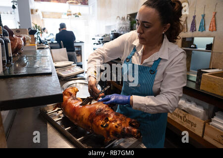 Frau vorbereiten ein Ferkel, die in traditionelle portugiesische Bairrada Weise geröstet wurde für den Dienst an der Rei Dos Leitões Restaurant, Setúbal, Portugal Stockfoto