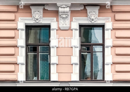 Zwei rechteckigen Fenstern mit bas-relief, gegen eine rosa Wand mit weißem Stuck. Aus einer Reihe von Windows von Sankt-petersburg. Stockfoto