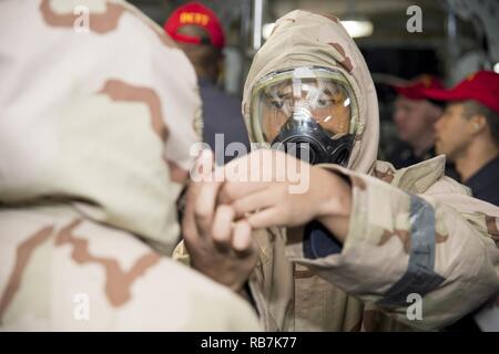 SASEBO, Japan (31. 6, 2016) Petty Officer 2nd class David Sacdal, aus San Francisco, Calif. Unterstützt Petty Officer 3rd Class Laniece Watters, von Columbus, Ohio, Don gemeinsamen Dienst leichte integrierte Anzug Technologie (JSLIST) während eines chemischen, biologischen, radiologischen Bohren an Bord amphibisches Schiff USS BONHOMME RICHARD (LHD6). Bonhomme Richard, Vorwärts- und Sasebo, Japan bereitgestellt, das eine schnelle Reaktionsfähigkeit im Falle eines regionalen Kontingenz oder Naturkatastrophe zur Verfügung zu stellen. Stockfoto