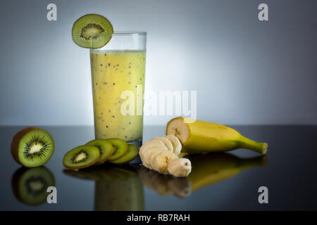 Frische und saftige Banane und Kiwi Smoothie in Glas mit Früchten um - Hohe Qualität gesunde Konzept auf schwarzen und grauen Hintergrund Stockfoto