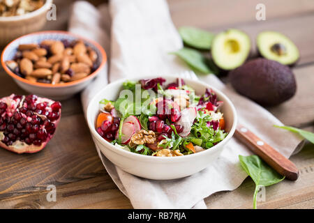 Frische, gesunde und oragnaic Salat mit Spinat, Rucola Blätter, Rettich, Tomaten, Bio Nüsse und Granatapfel Samen. Salat vegan Diät Konzept Stockfoto