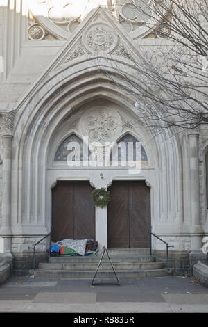 Obdachlosen schläft auf den Stufen einer Kirche entlang der 7. Avenue in Park Slope, Brooklyn während der Weihnachtszeit. Stockfoto