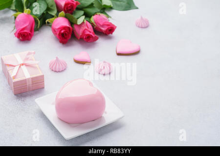 Romantisches Frühstück Konzept mit herzförmigen Mousse Cake, Geschenkbox und Blumen im Hintergrund für Valentines Tag. Kopieren Sie Platz. Stockfoto