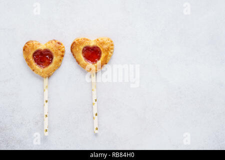 Herzförmige Torte Pops mit Erdbeermarmelade. Hausgemachte Kekse Cookies auf einen Stick für den Valentinstag. Stockfoto