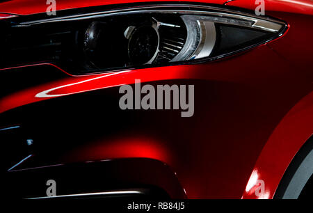 Closeup Scheinwerfer von glänzend rot Luxus-SUV Compact Car. Elegante Elektroauto Technologie und Business Konzept. Hybrid auto und Kfz-Konzept. Auto Stockfoto