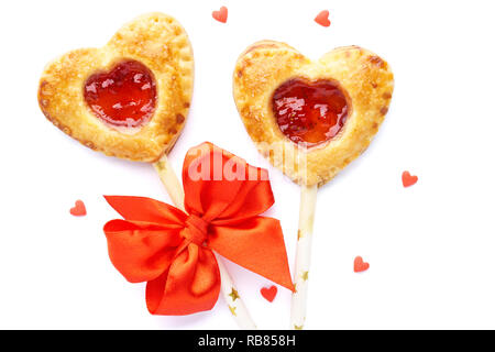 Herzförmige Torte Pops mit Erdbeermarmelade. Hausgemachte Kekse Cookies auf einen Stick für den Valentinstag. Isoliert. Ansicht von oben. Stockfoto