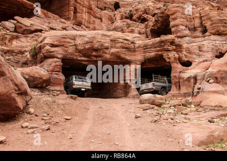 Off-road Fahrzeuge stehen in faszinierenden regenbogenfarbenen Mulden der Höhlen in antike Stadt Petra, Jordanien Stockfoto