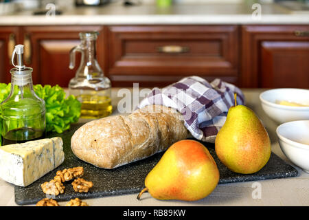 Ciabatta Brot, Käse, grüner Salat, Birnen, Nüsse, Honig und Olivenöl auf den Tisch Stockfoto