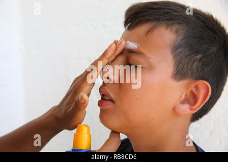 Mutter, Sonnencreme auf dem Gesicht ihres Sohnes im Salento, Italien. Stockfoto