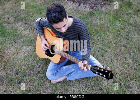 Junge Mann spielt eine Gitarre in einem Garten. Frankreich. Stockfoto