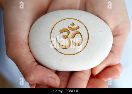 Die Om oder Aum Symbol von Hinduismus und Buddhismus auf einen weissen Stein. Stockfoto