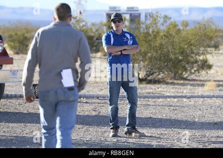 Casey Kleisinger, ein Mitglied des Teams von Robins Air Force Base, Ga, Signale einer Mitmannschaftskamerad während ein Szenario als Teil der 2016 Air Force Research Laboratory Kommandeure Herausforderung am Nevada National Security Website, Las Vegas, NV., Dez. 13, 2016. Mannschaften wurden sechs Monaten eine komplette Zähler - Unmanned Aerial Systems in Base Defense zu Hilfe zu entwickeln. Robins' system ist eine vielschichtige integriertes System verwendet ein Radar und Kamera System für den Nachweis und die Identifizierung. Es verwendet auch ein Hunter killer Drohnen für die Überwachung des Fernmeldeverkehrs und Wasserwerfer für Aufnahmen aus dem Himmel. Stockfoto