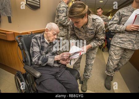 Master Sgt. Jamie Nieves, Mitte, Bauingenieur 177th Squadron, gibt Armee Weltkriegveteran Charles Crabiel der Karte während des 16. jährlichen Urlaub ongfest' an der New Jersey Veterans Memorial Home in Vineland, N. J., Dez. 13, 2016. Mehr als 80 Viertklässler aus der Seaview Volksschule in Linwood, N.J., und 18 Flieger sang holiday Songs und ausgeteilten Karten zu den Bewohnern des Hauses während der Veranstaltung. Stockfoto