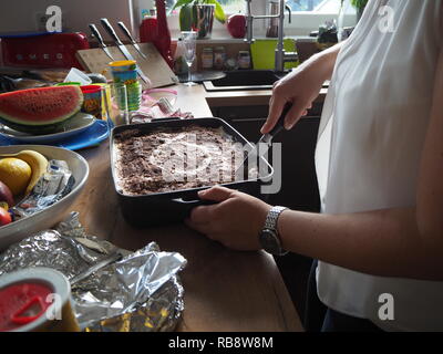 Haus Frau Schneid- und Vorbereitung von Tiramisu. Stockfoto