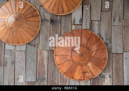 Weave Hut aus Bambus und Palmblättern hängen auf Holz Wand Hintergrund. Stockfoto