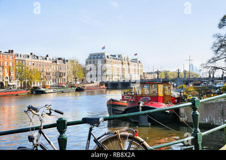 Blick entlang der Amstel in Richtung Hogesluis Brücke und InterContinental Amstel Hotel, Amsterdam, Nordholland, Niederlande Stockfoto