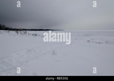 Die Spur im Schnee, die in das offene Meer auf dem Hintergrund der dunklen Winter Abend Himmel führt Stockfoto