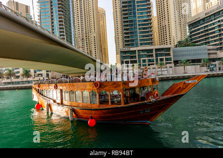 Dubai, VAE 11. 10. 2018: die berühmte traditionelle Holz- alten Dhow Cruise tour in der Marina mit Touristen auf dem Board und moderne Wolkenkratzer in der backgou Stockfoto