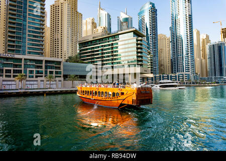 Dubai, VAE 11. 10. 2018: die berühmte traditionelle Holz- alten Dhow Cruise tour in der Marina mit Touristen auf dem Board und moderne Wolkenkratzer in der backgou Stockfoto