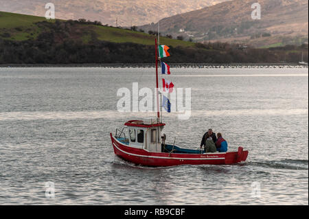 Bantry, West Cork, Irland. Januar 2019. Am 40. Jahrestag der Katastrophe von Whiddy Island, in der der französische Öltanker Betelgeuse 50 tötete, nahm eine riesige Menschenmenge an den Formalitäten im Abbey Graveyard, Bantry, Teil. Ein Boot mit der irischen, französischen, kanadischen und EU-Flagge segelt mit Verwandten der Toten an Bord nach Whiddy. Credit: AG News/Alamy Live News. Stockfoto