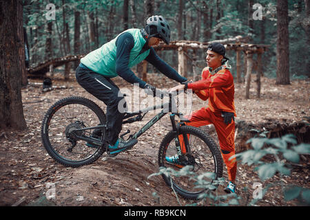 Moskau, Russland - Nov, 2018: MTB-Lehrer helfen Reiter lernen, Fahrrad zu fahren. Lehre ein Reiter, ein Fahrrad auf einem Trail zu fahren. Zwei Freunde haben Spaß in der Natu Stockfoto