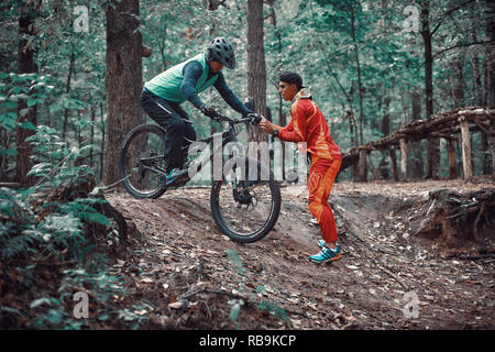 Moskau, Russland - Nov, 2018: MTB-Lehrer helfen Reiter lernen, Fahrrad zu fahren. Lehre ein Reiter, ein Fahrrad auf einem Trail zu fahren. Zwei Freunde haben Spaß in der Natu Stockfoto