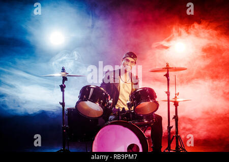 Zuversichtlich gemischt Rennen männlichen Musiker sitzen auf der Bühne mit Scheinwerfern drum Set Stockfoto