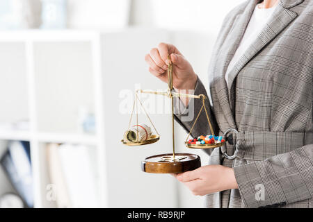 Zugeschnittenes Bild von Rechtsanwalt Justiz Skalen mit Geld und Drogen auf Tisch im Büro Stockfoto